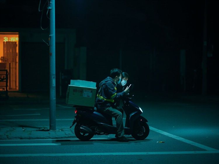 夜路上的快递员，停在车边低头看手机